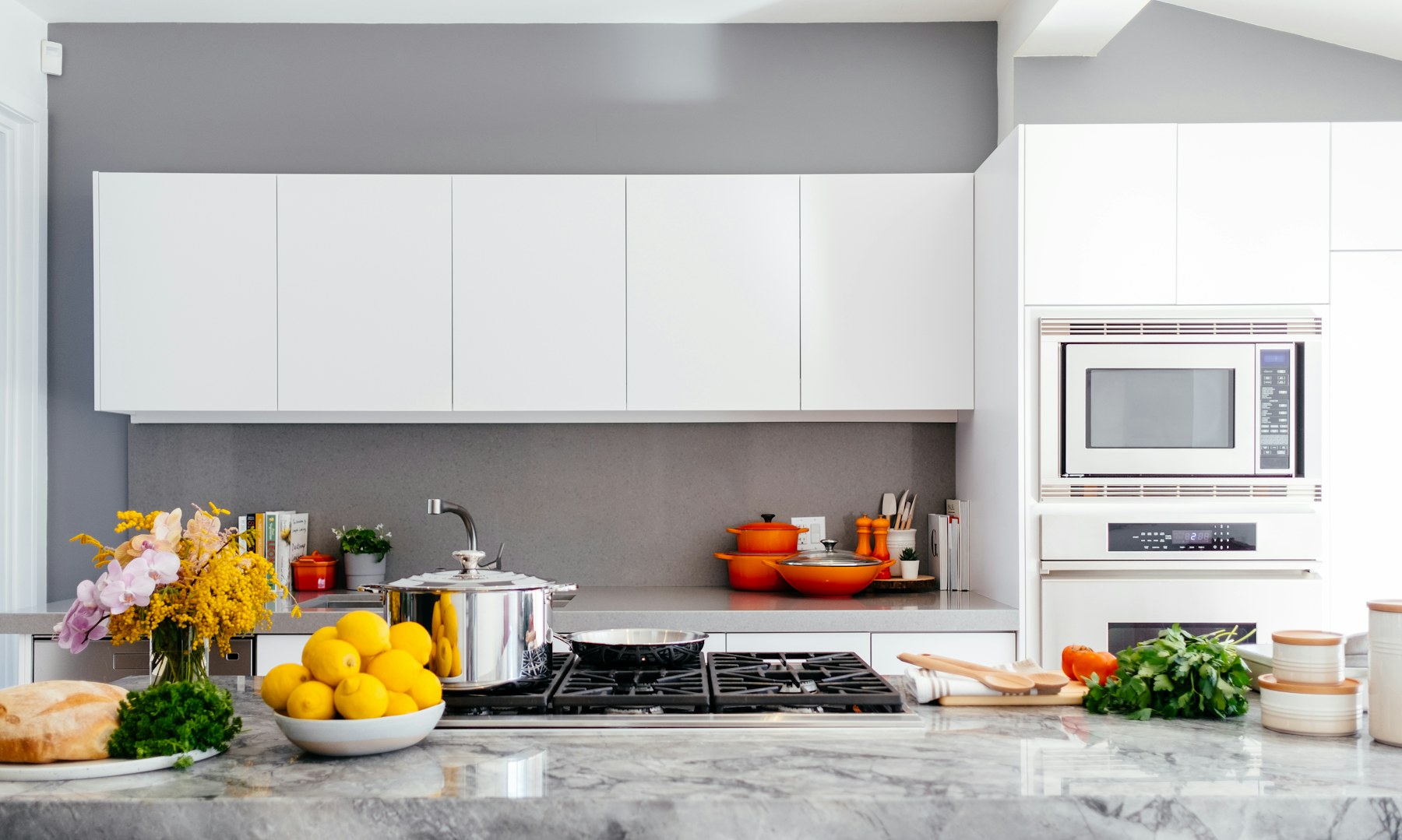 A bright modern kitchen with pale cabinetry and stone worktops