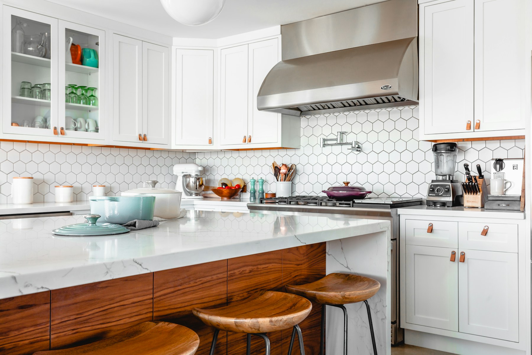 White kitchen cabinetry, stone island and timber stools